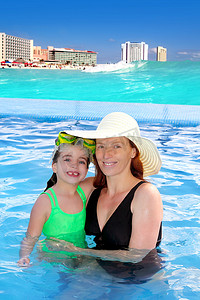 母亲和女儿在热带海滩泳池拥抱