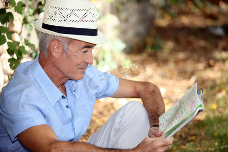 老人坐在地上摄影照片_65岁老人坐在草地上看书