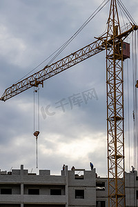 工队摄影照片_一队建筑工人和一台起重机在傍晚多云的天空背景下建造建筑物。