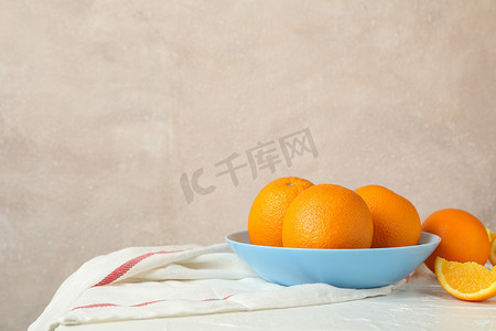 浅色背景的白桌上放着橙子和厨房毛巾的盘子，文字空间