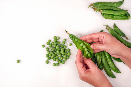 蔬菜清洗摄影照片_用手顶视图清洗新鲜的豌豆，反对白色背景。