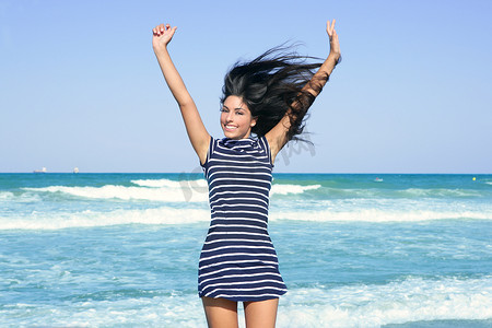 美丽的夏日黑发女孩在沙滩上跳跃