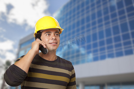 西班牙裔男性承包商在大楼前打电话