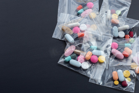 拉链线稿摄影照片_五颜六色的药片，胶囊和药丸在深色背景的医药塑料拉链锁袋中。