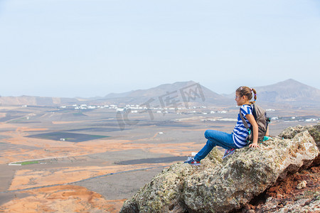 女孩仰望天空摄影照片_“女孩坐在悬崖边，仰望天空”