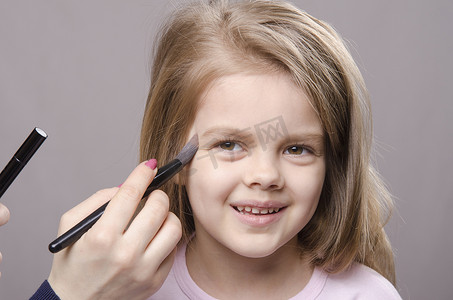 儿童脸上摄影照片_化妆师在女孩脸上撒粉