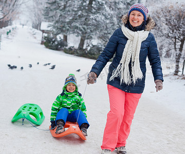 玩雪橇的孩子摄影照片_一家人在冬季公园玩雪橇