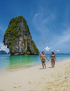 莱雷海滩甲米泰国，莱雷甲米热带海滩，海滩上的情侣男女，泰国田园诗般的莱雷海滩全景，乘坐传统的长船