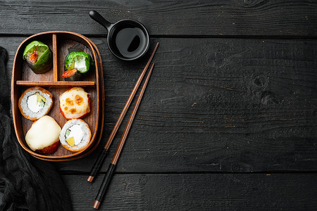 日式平铺摄影照片_带筷子的日式便当午餐盒，黑色木桌背景，顶视图平躺，带复制空间和文本空间