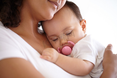 母亲怀抱的安全......睡在母亲怀里的女婴特写。