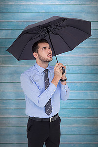 焦虑的商人用雨伞避难的合成图像