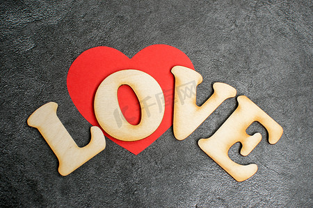 情人节艺术字摄影照片_情人节卡片背景，红色可爱的心形纸制成，深色背景上装饰木字。