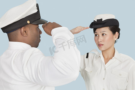 海军敬礼摄影照片_多民族美国海军军官在淡蓝色背景中互相敬礼