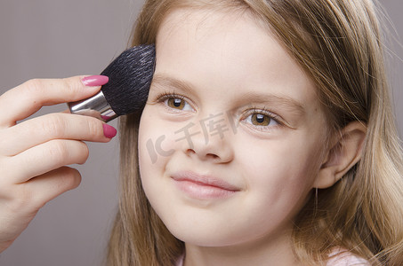 化妆师在女孩脸上撒粉