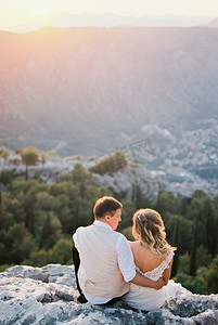 新娘和新郎坐在山顶，望着山谷