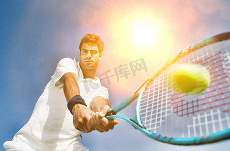 黄色球光晕摄影照片_坚定的年轻人用黄色镜头光晕打网球的低视角