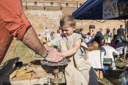 乌克兰，卢茨克 — 2019 年 6 月 5 日：一个成年男子的手教孩子如何在美食节上用陶轮上的一块粘土制作一个水壶。
