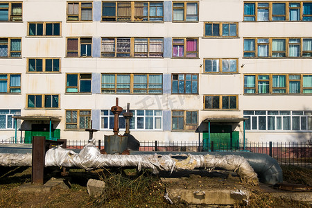 俄罗斯一栋公寓楼矗立在供暖管道前