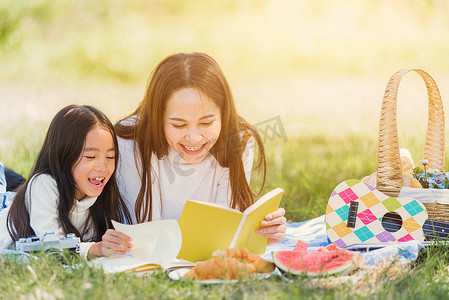 快乐的家庭，享受户外的乐趣，躺在野餐毯上看书