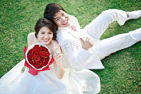 玫瑰田摄影照片_新娘和新郎的肖像坐在新鲜的草地上与玫瑰 bou