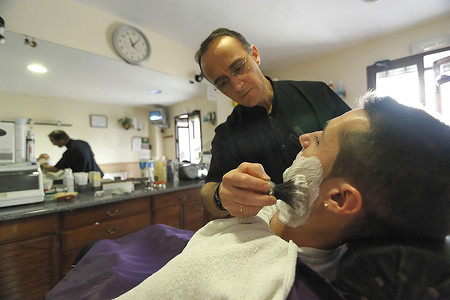 在西班牙安达卢西亚哈恩省萨比奥特的一家理发店里，理发师用刷子剃须泡沫给年轻人剃须