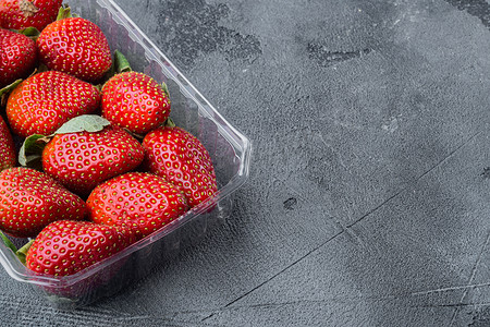 透明塑料托盘中的红色熟草莓，灰色背景，带文本复制空间