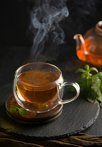 绿色茶壶摄影照片_茶的概念，木背景中茶壶，茶道，透明杯中的绿茶