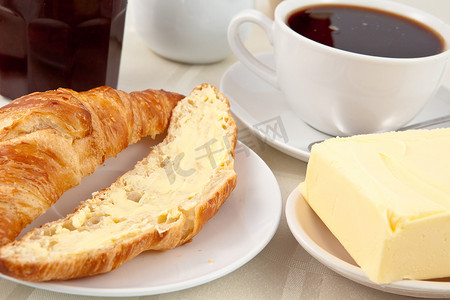 酒店桌布摄影照片_早餐包括涂有黄油的羊角面包