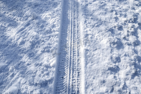 雪街道摄影照片_近距离观察积雪覆盖的街道上的轮胎痕迹。