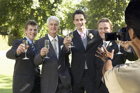 敬酒的人摄影照片_男人拍下五个男人在婚礼上用酒杯敬酒的照片