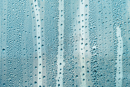 彩色雨滴背景摄影照片_带有蓝色水滴的抽象背景装饰品。雨滴是蓝色的。玻璃上闪闪发亮的水面。水滴呈球形或球形。彩色雨滴背景