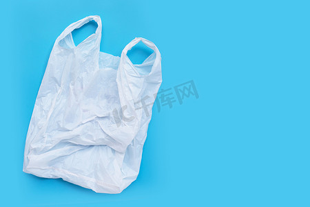 可降解塑料袋摄影照片_蓝色背景上的白色塑料袋。