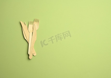 绿色居家背景摄影照片_绿色背景中用于快餐和野餐的一次性木叉和刀