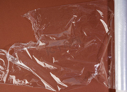 瘦包装摄影照片_棕色背景包装用透明保鲜膜卷