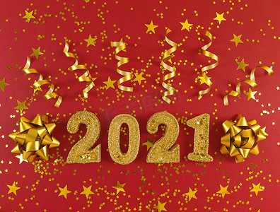 2021 年新年贺卡。红色背景上闪闪发光的金色人物、星星、蝴蝶结和丝带。