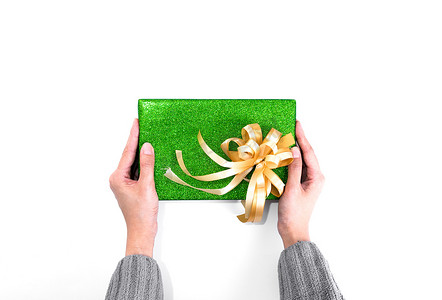 拿着带绿色闪光包装纸的圣诞礼物和