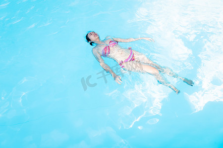 美丽的亚洲女人喜欢在游泳池里游泳