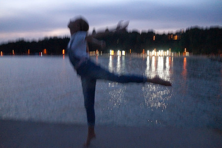 模糊的照片，赤脚少女晚上在空荡荡的码头上跳芭蕾舞