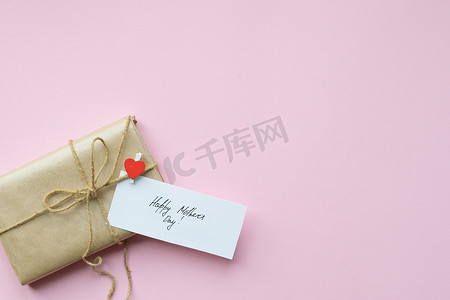 用棕色牛皮纸包裹的礼物，在浅粉色背景上系上麻绳。