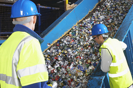 两名工人在工业中监测回收罐的传送带