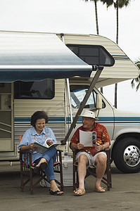 老年夫妇坐在椅子上，背景是大篷车