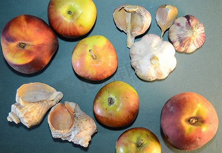 苹果桃子摄影照片_苹果、桃子、大蒜和贝壳 — 蓝色皮肤背景中的静物