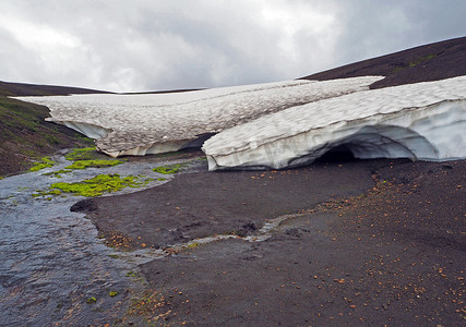 冰岛雪冰洞和溪流，在悲伤的荒凉景观中，长着鲜绿色的苔藓