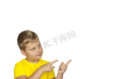 一个身穿黄色 T 恤、白色背景的男孩用手指指着什么。