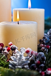 插花圣诞摄影照片_在出现插花的三个燃烧的蜡烛