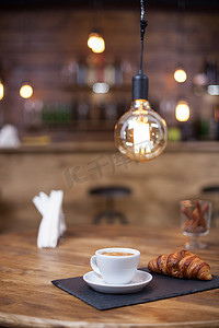 玛奇朵摄影照片_在老式咖啡店享用一杯美味的拿铁玛奇朵和美味的羊角面包