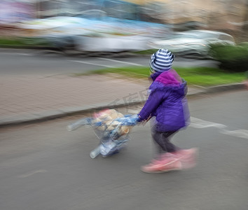 孩子过马路摄影照片_推着婴儿车过马路的小女孩