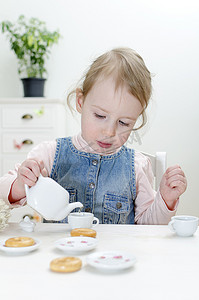 可爱的小女孩喝着百吉饼的茶