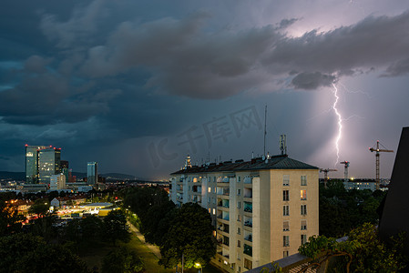 猛烈摄影照片_维也纳维纳贝格市上空出现猛烈的夏季雷暴和巨大的闪电，图片右侧有建筑起重机