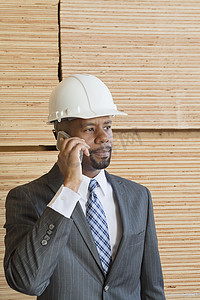 非洲裔美国男工程师打电话，背景是堆叠的木板